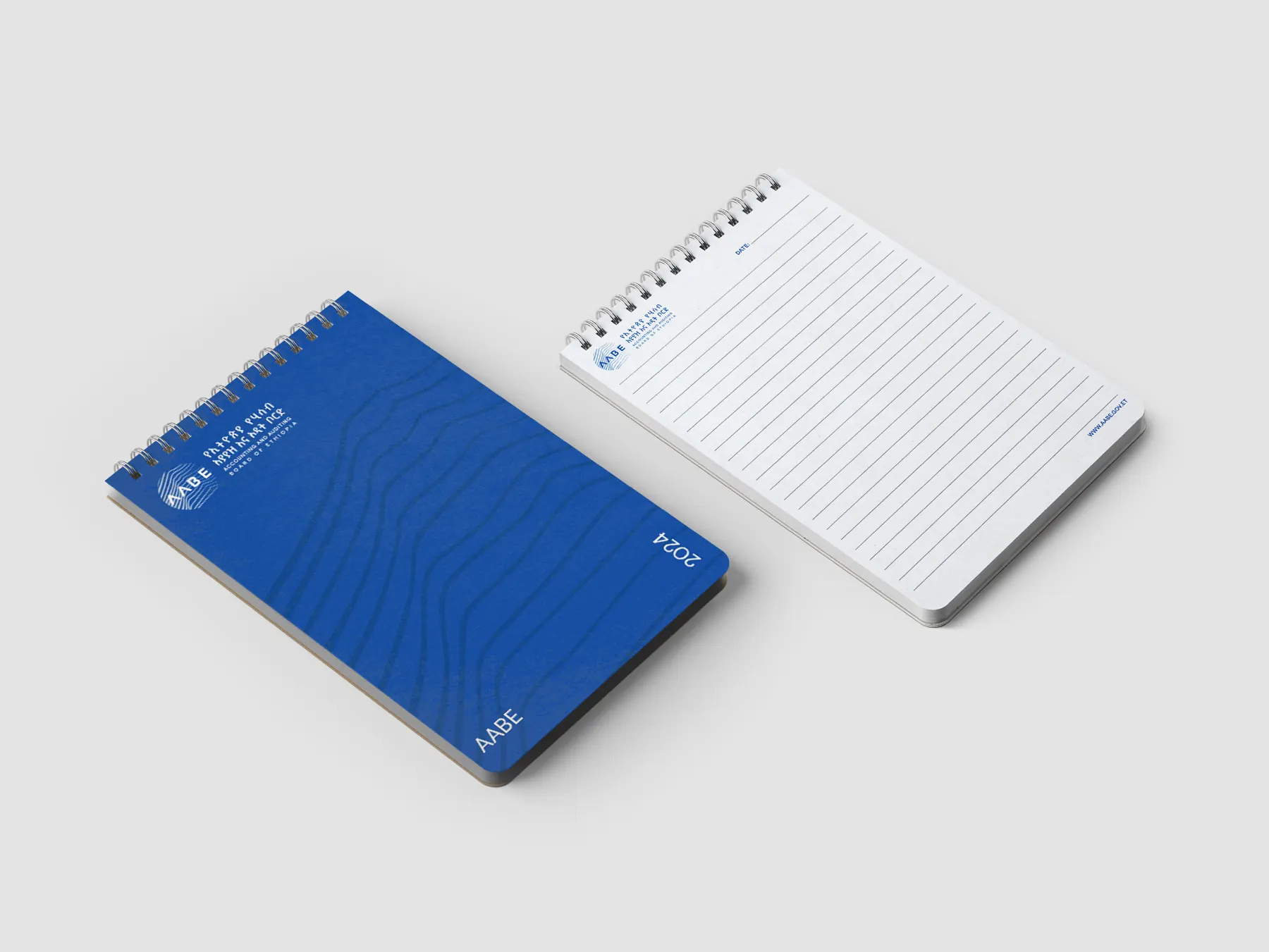 A blue AABE notepad with the line pattern beside a lined white pad.