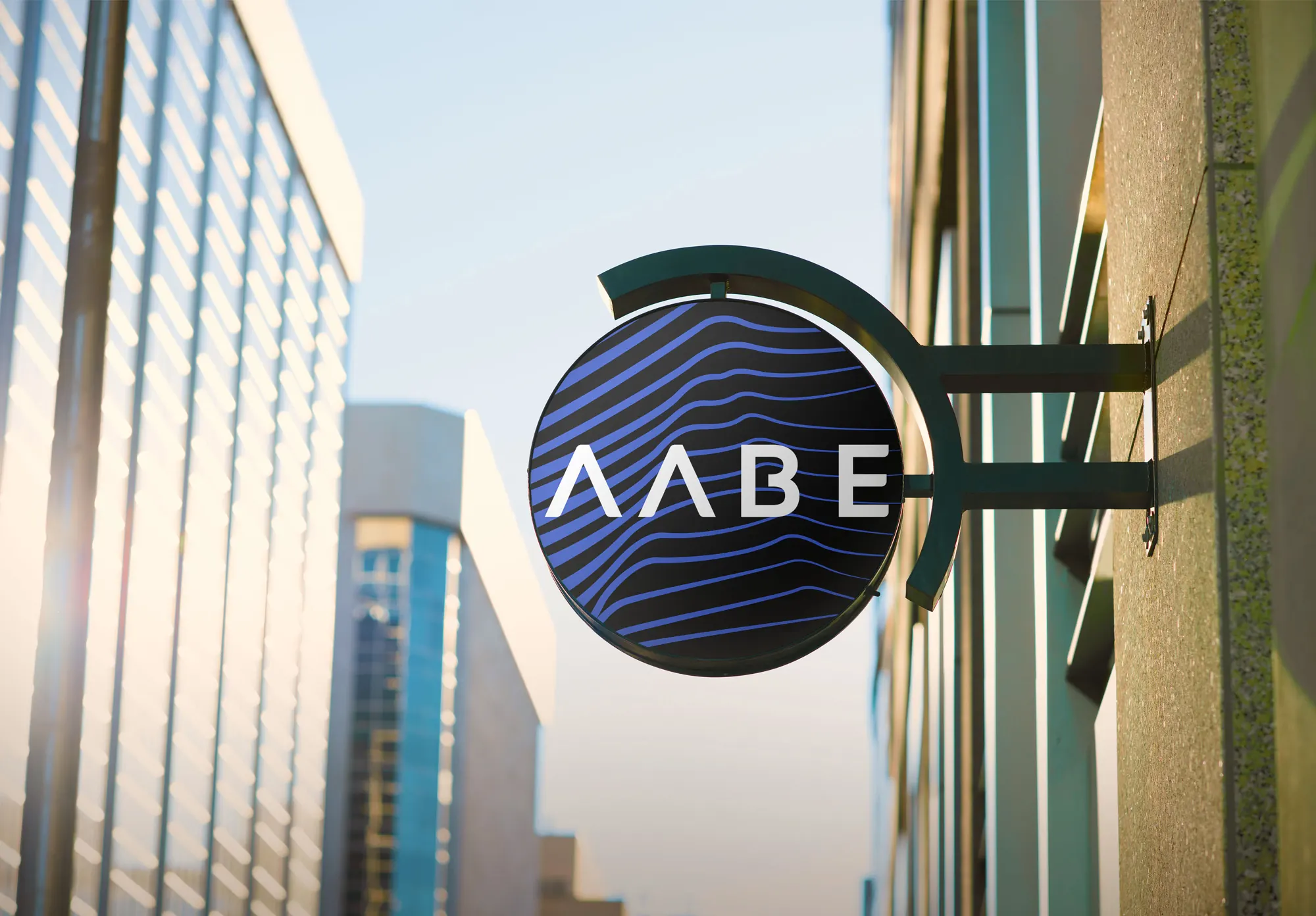 A round projecting sign on a city building: white AABE initials over blue flowing lines on black.