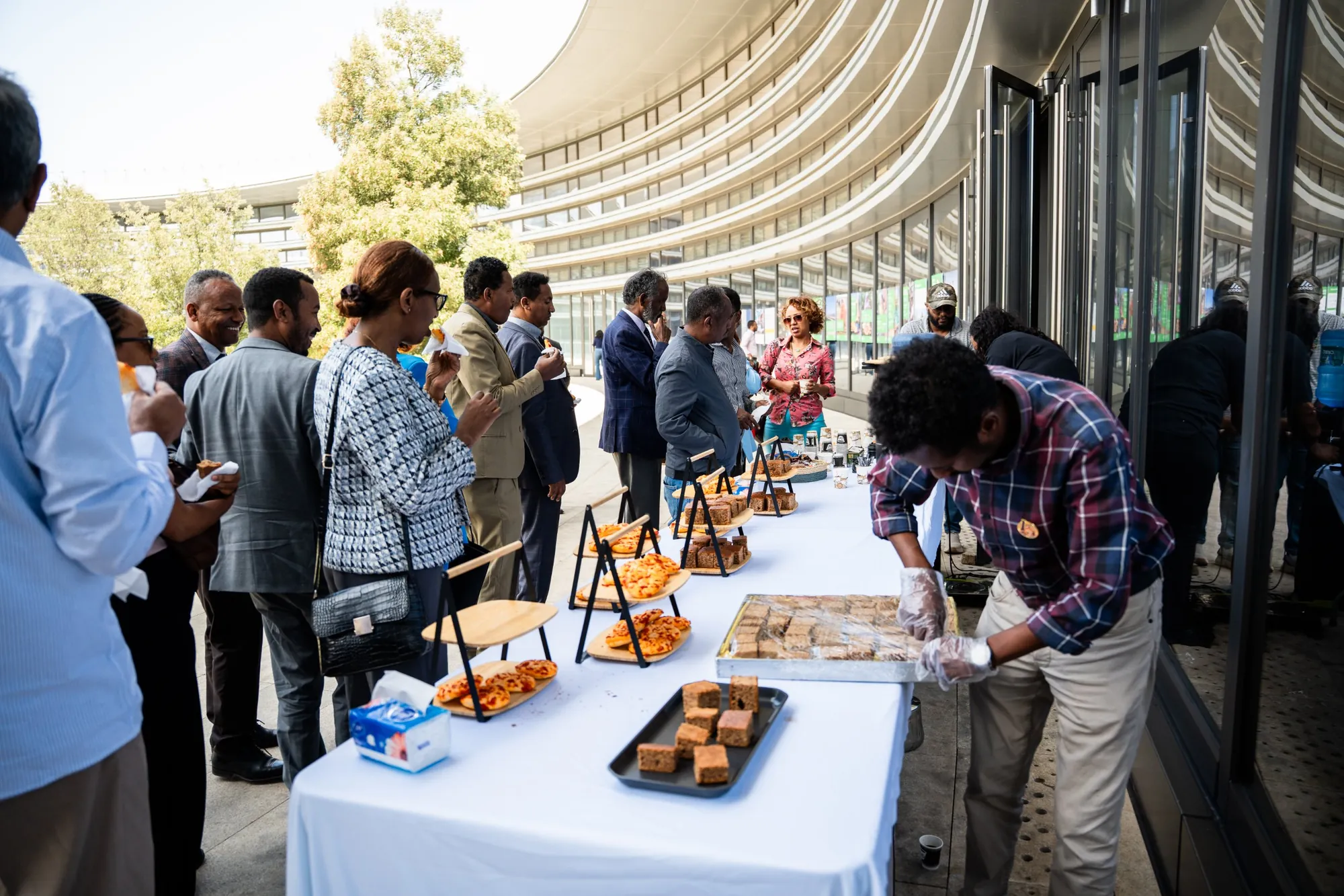 Guests at the refreshments table on the terrace beside the museum’s curved glass façade.