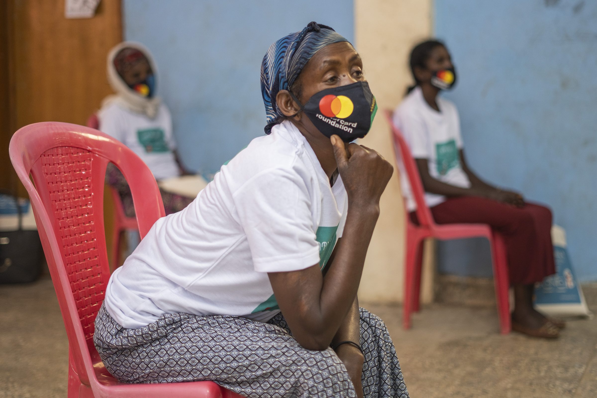 A coffee vendor in a campaign mask and T-shirt listens during a health session.
