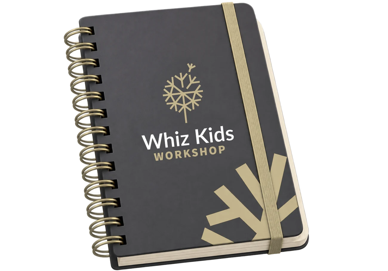 A charcoal spiral notebook with gold rings and a gold elastic band; the Whiz Kids Workshop logo on the cover and large gold branch shapes in the corner.