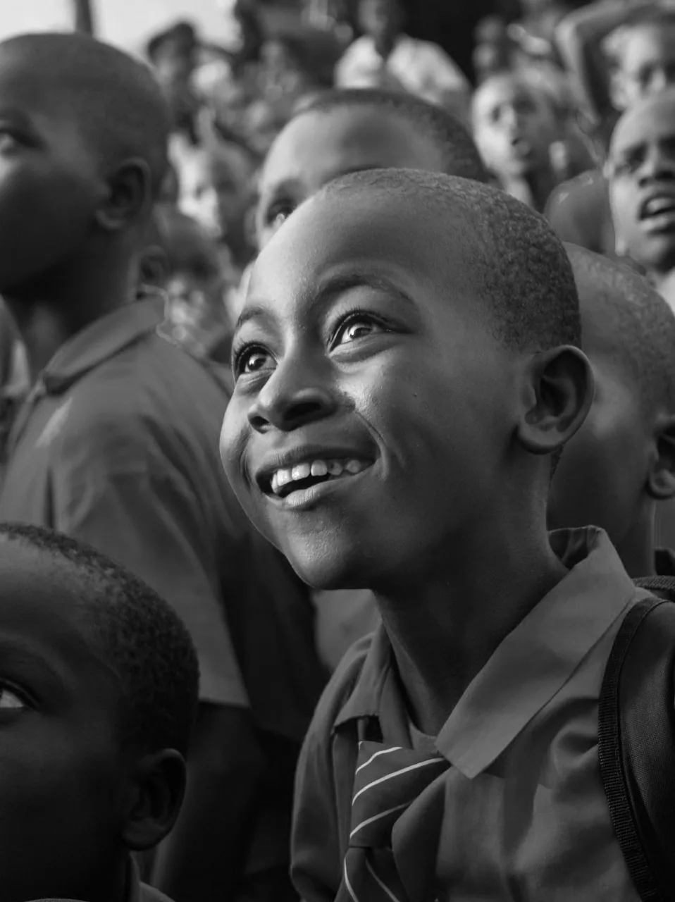 Black and white photograph of a smiling boy looking up, from the Whiz Kids brand image system.